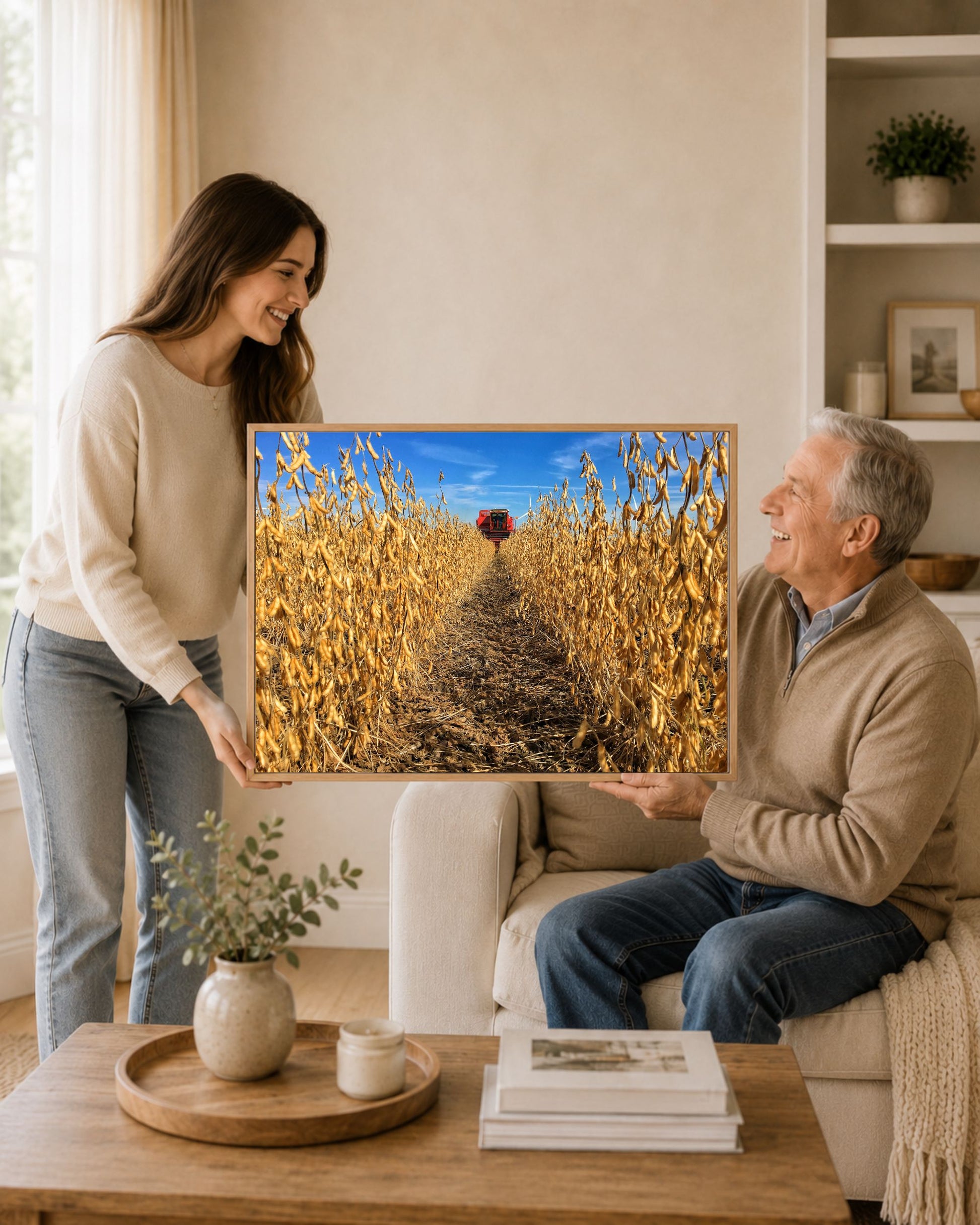 Woman gifting an oak framed soybean harvest canvas print to an older man in a warm neutral living room.