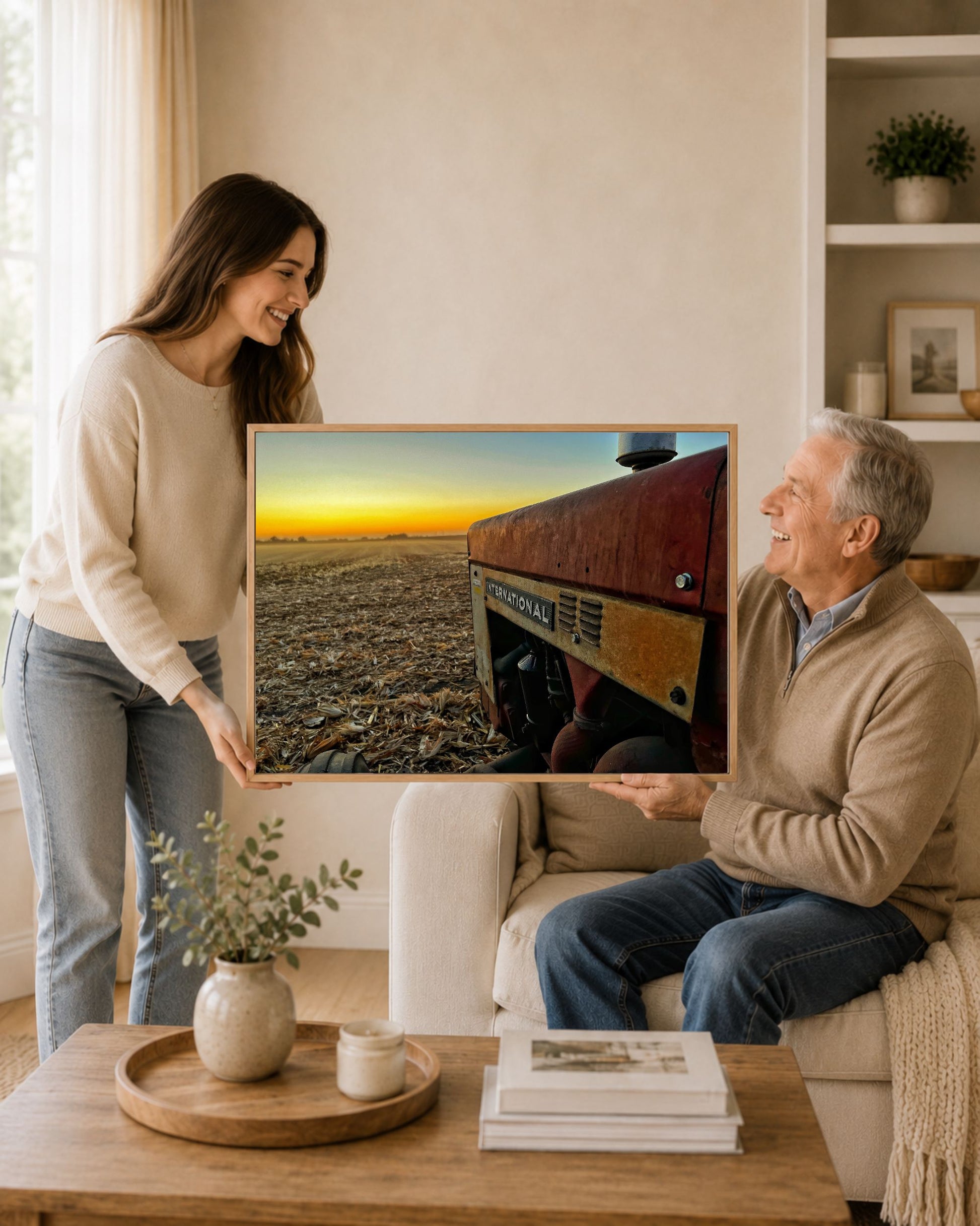 Woman gifting framed International tractor harvest sunset wall art to an older man in a warm living room setting.