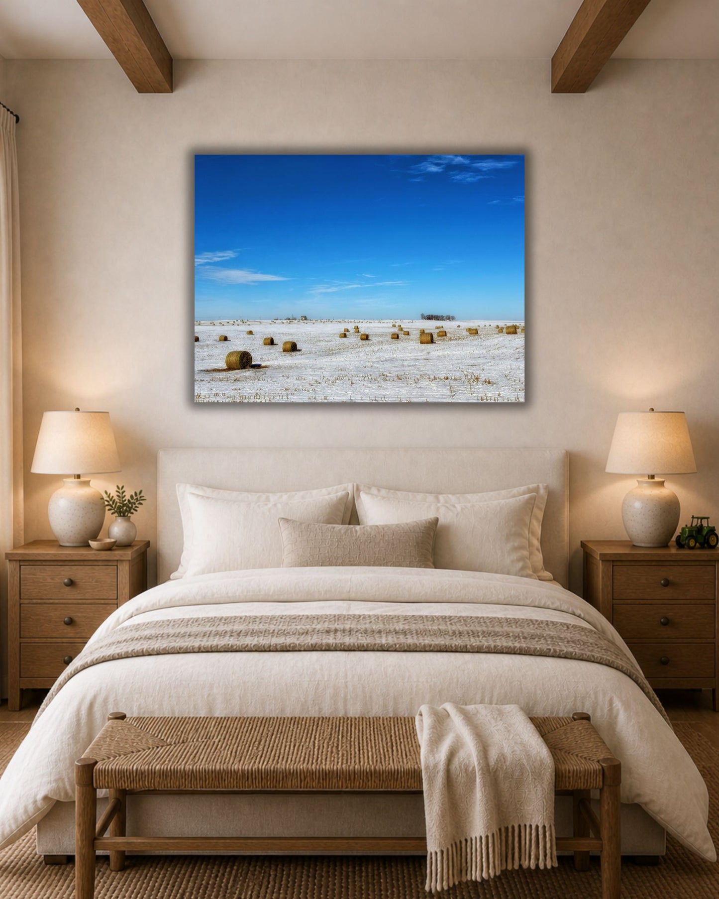 Snowy hay bale field canvas wall art displayed above a bed in a warm neutral farmhouse-style bedroom.