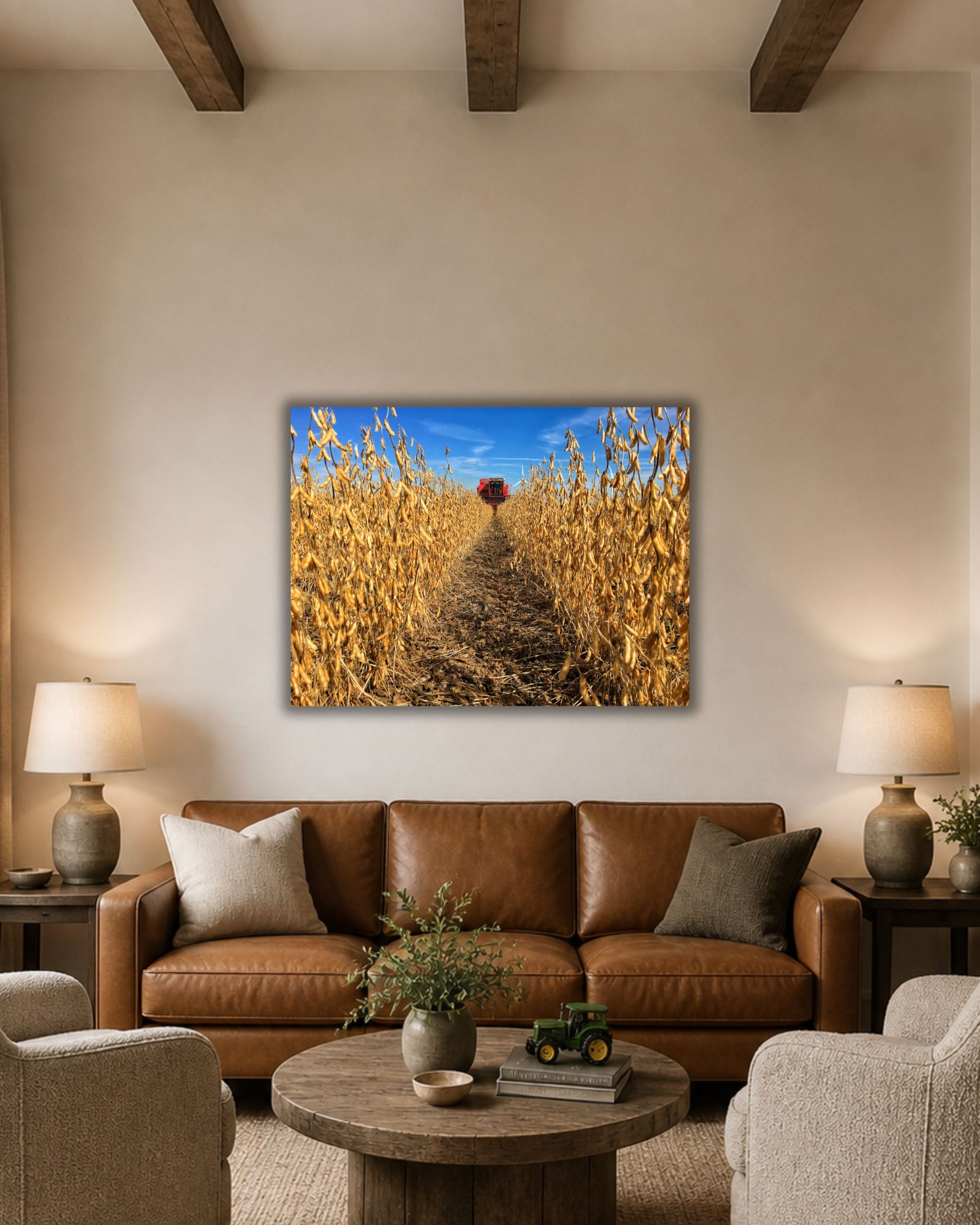 Soybean harvest canvas wall art displayed above a leather sofa in a warm farmhouse living room, featuring a red combine at the end of golden crop rows.
