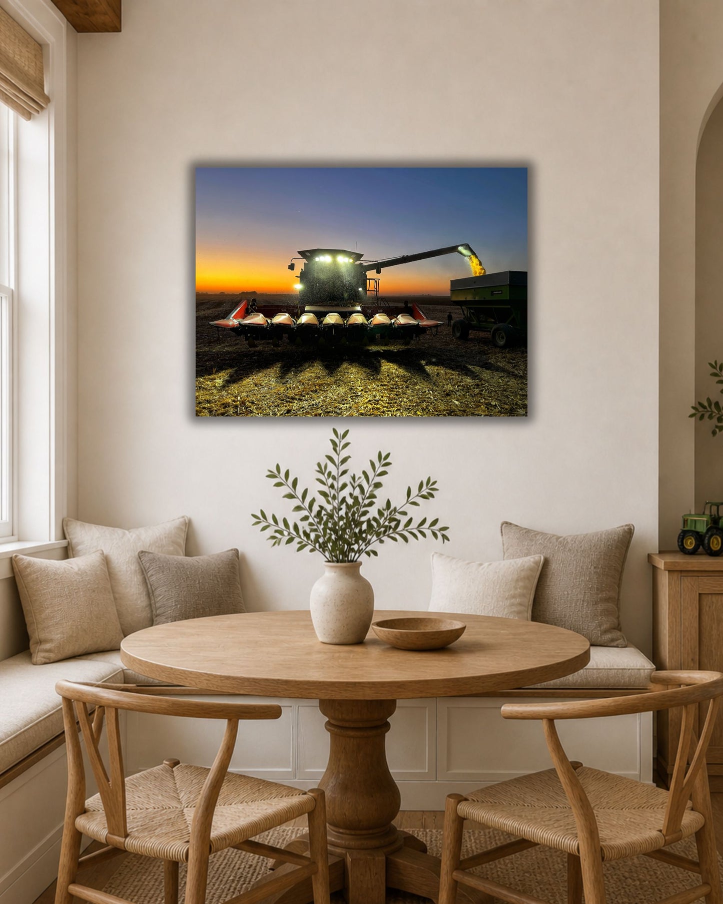 Natural oak framed harvest combine wall art displayed above two cream accent chairs in a warm neutral sitting area.