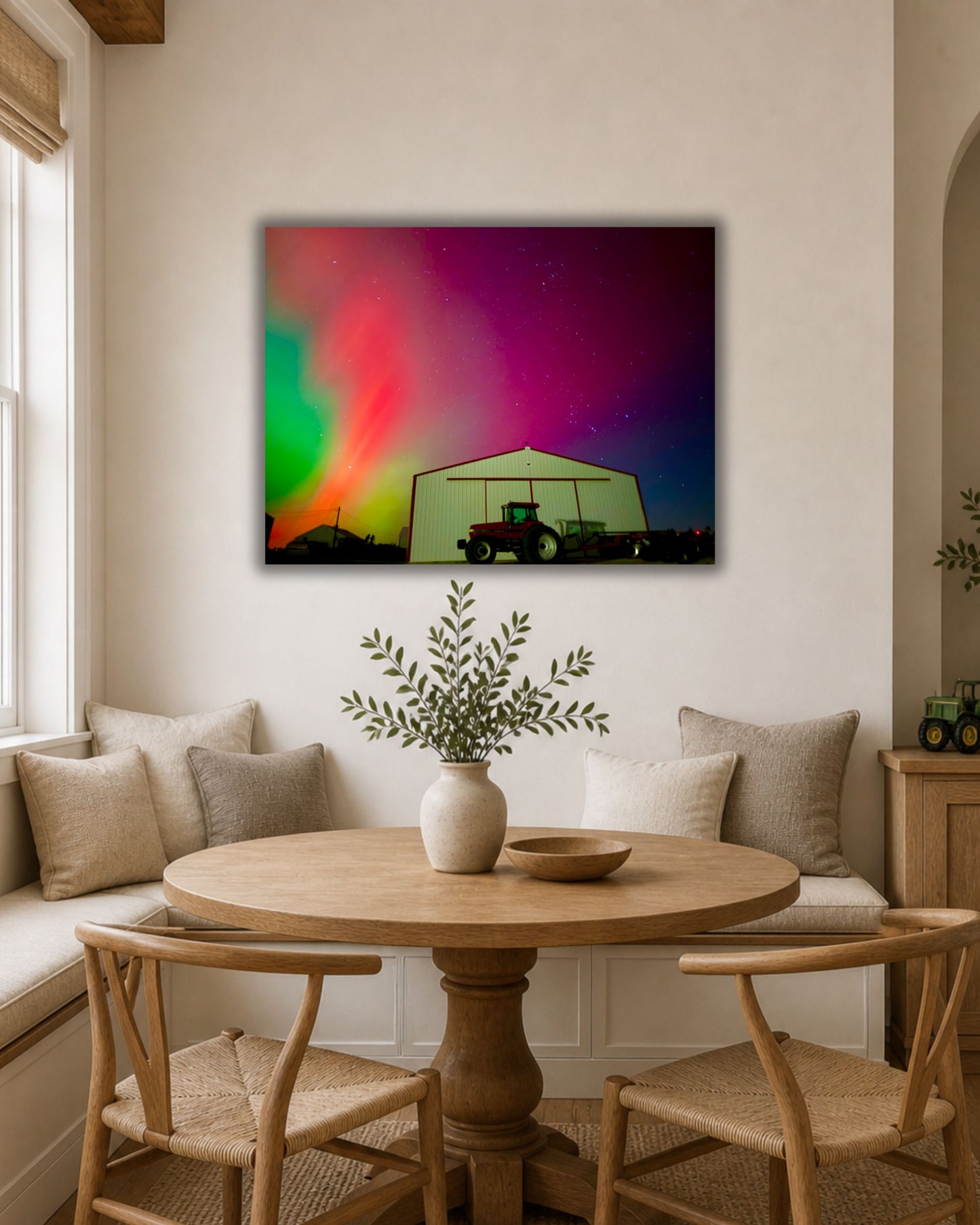 Northern lights farm canvas wall art displayed above a wooden dining nook in a warm neutral farmhouse-style room.