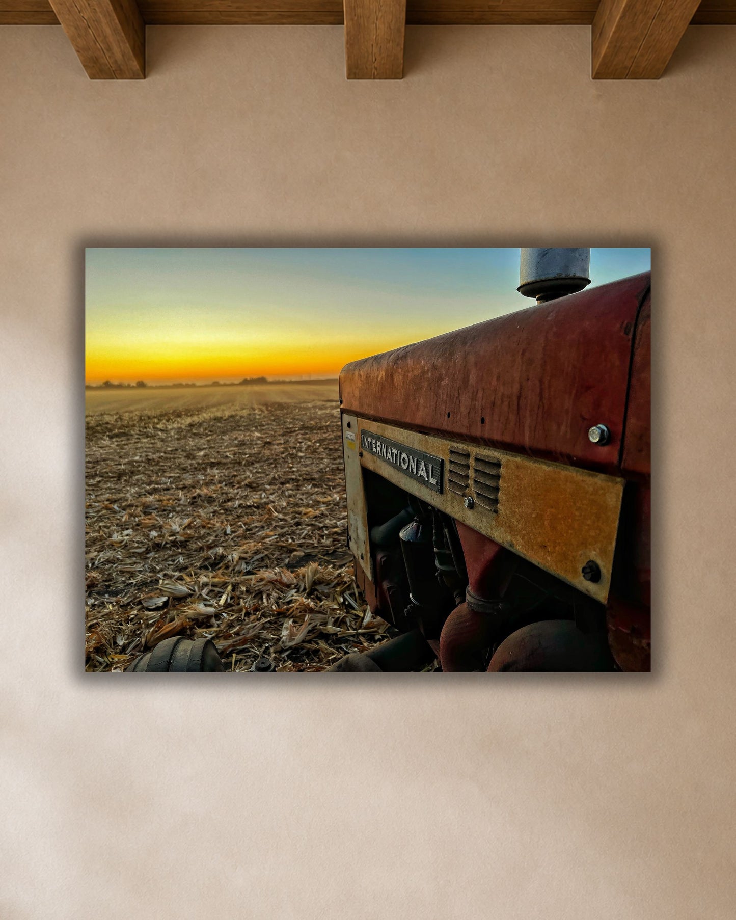 Vintage International tractor harvest sunset canvas wall art displayed above a warm wood dining table in a neutral farmhouse breakfast nook.
