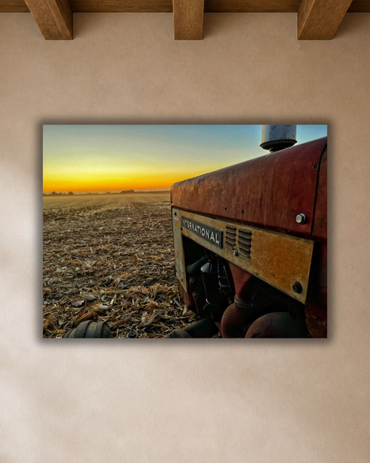 Vintage International tractor harvest sunset canvas wall art displayed above a warm wood dining table in a neutral farmhouse breakfast nook.