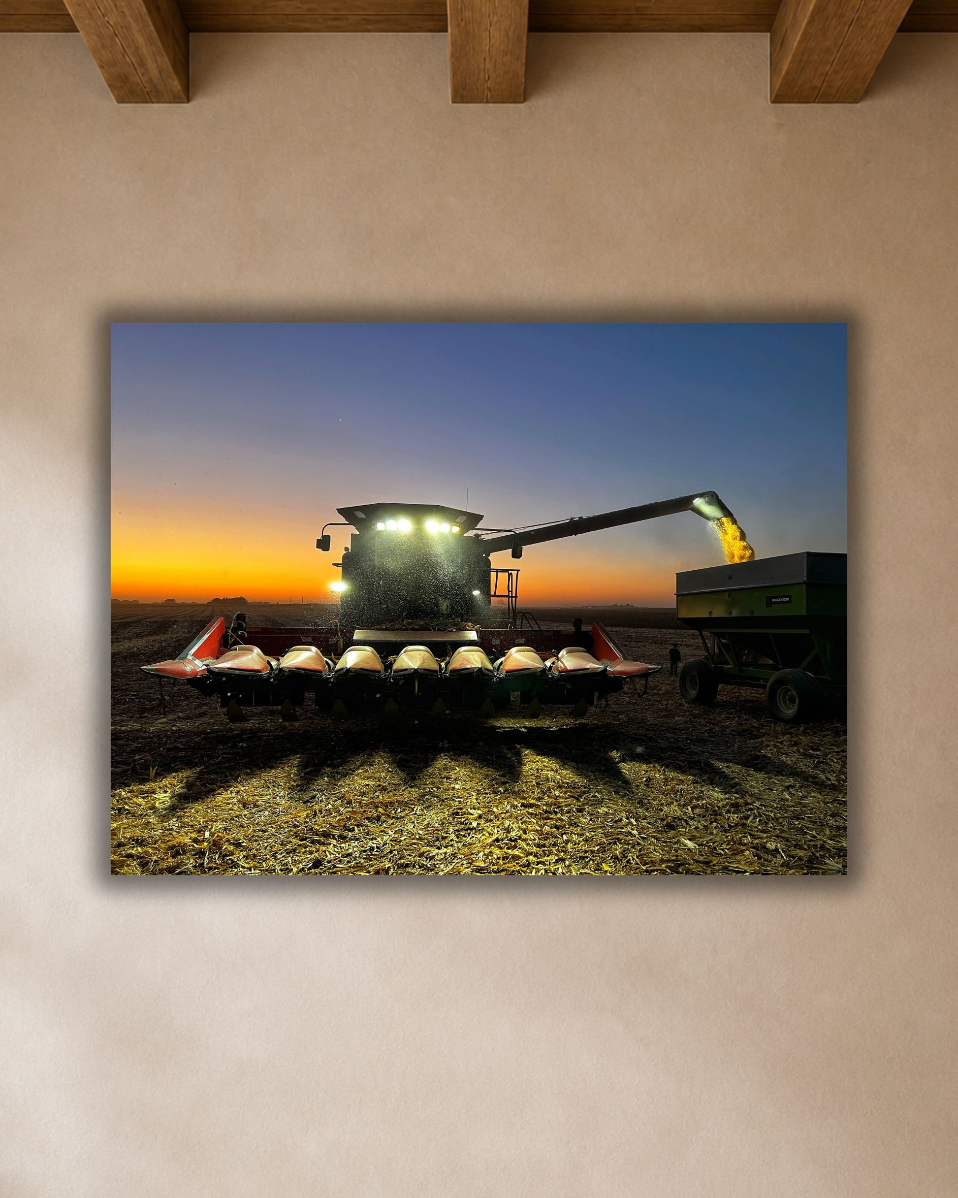 Harvest combine unloading corn at sunset canvas wall art displayed above a round dining table in a warm modern farmhouse breakfast nook.