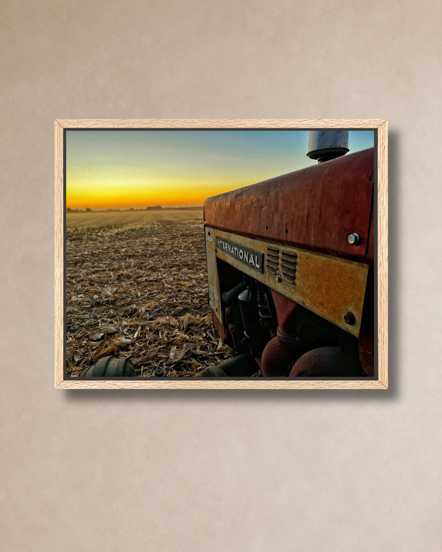 Close-up mockup of vintage International tractor at harvest sunset printed on gallery-wrapped canvas against a soft neutral wall.