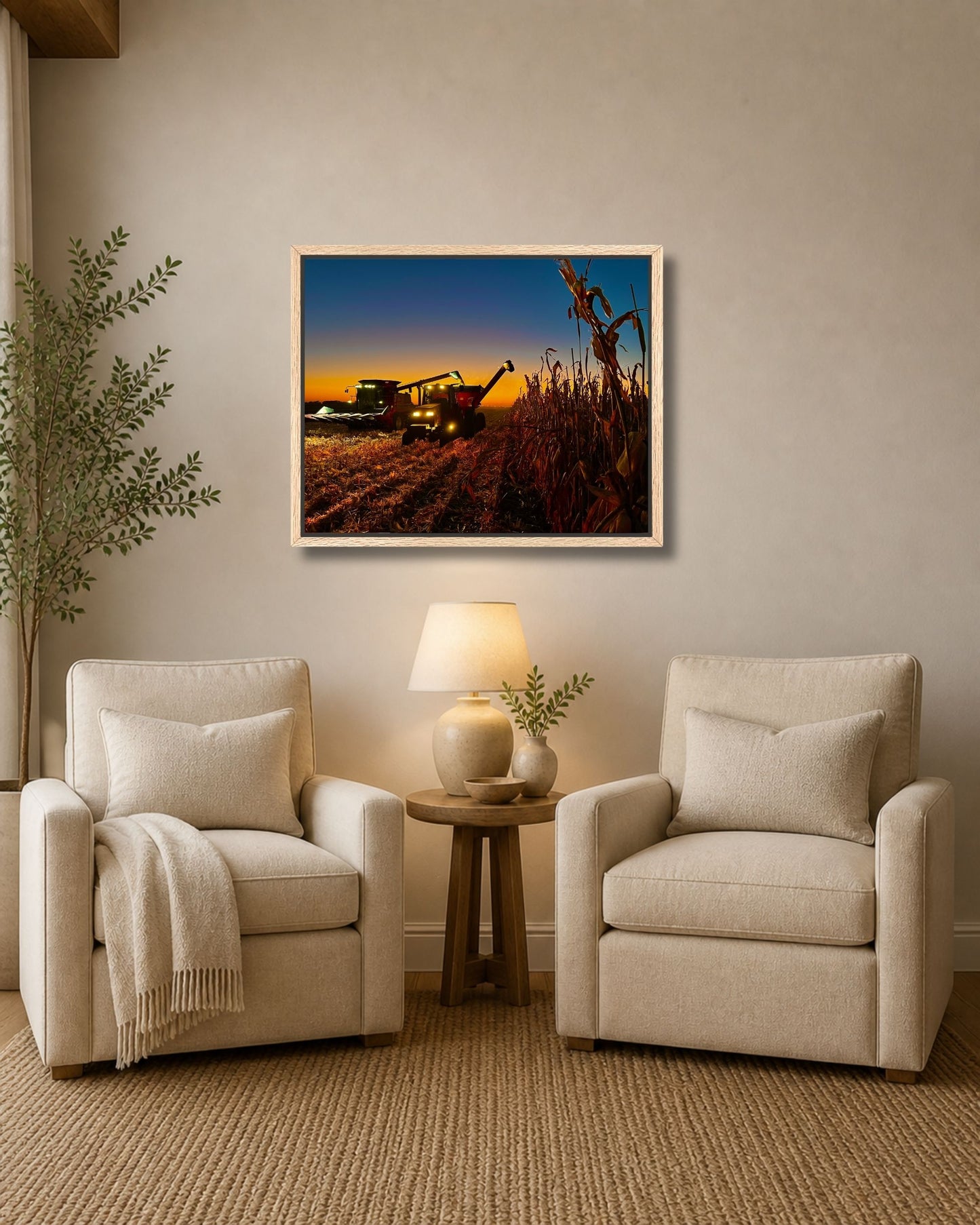 Natural oak framed corn harvest wall art displayed between two cream armchairs in a soft neutral sitting area.