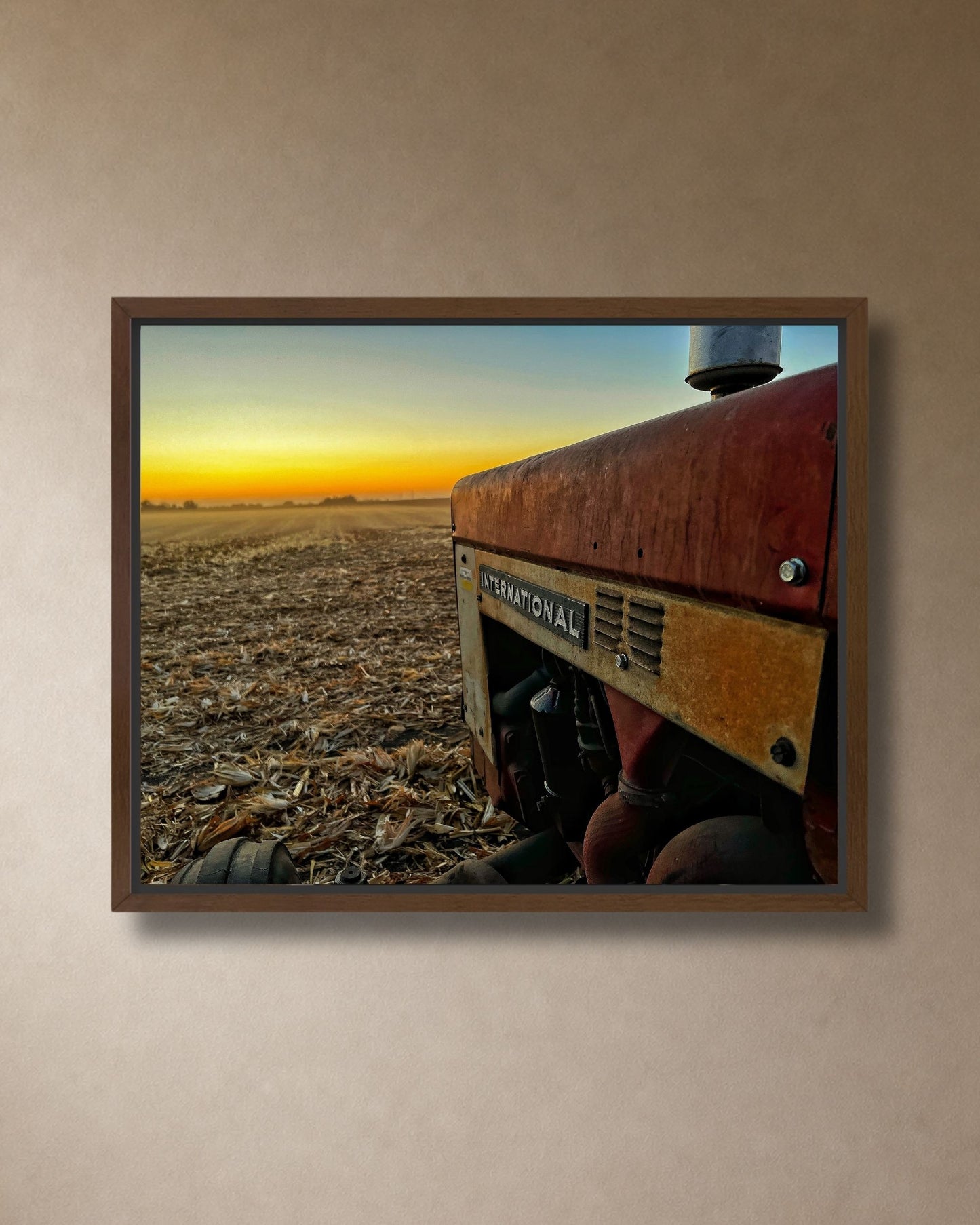 International tractor sunset farm photography canvas wall art styled above a natural stone fireplace in a cozy modern farmhouse living room.