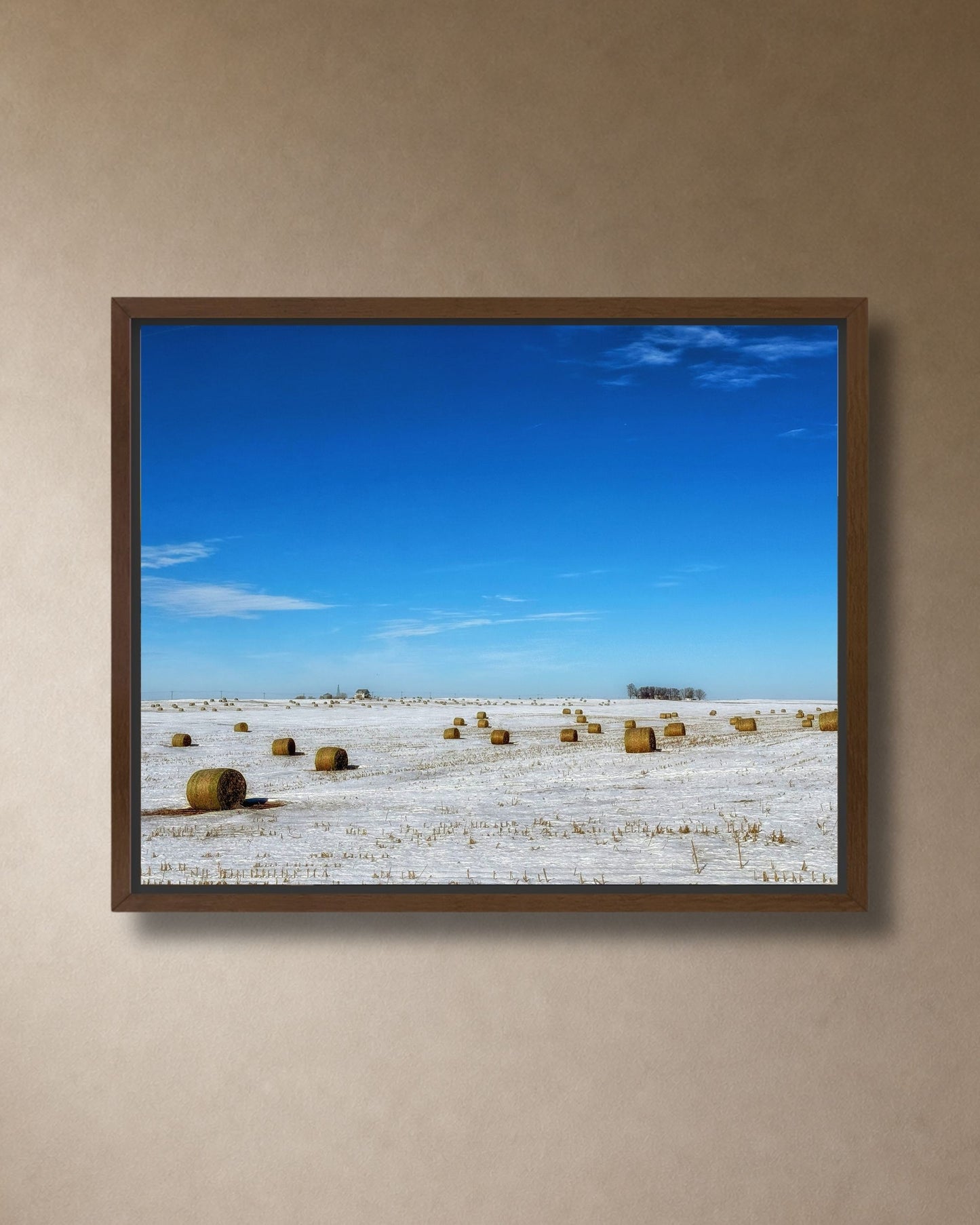 Walnut framed canvas print of hay bales resting in a snowy Midwest field beneath an open blue sky.