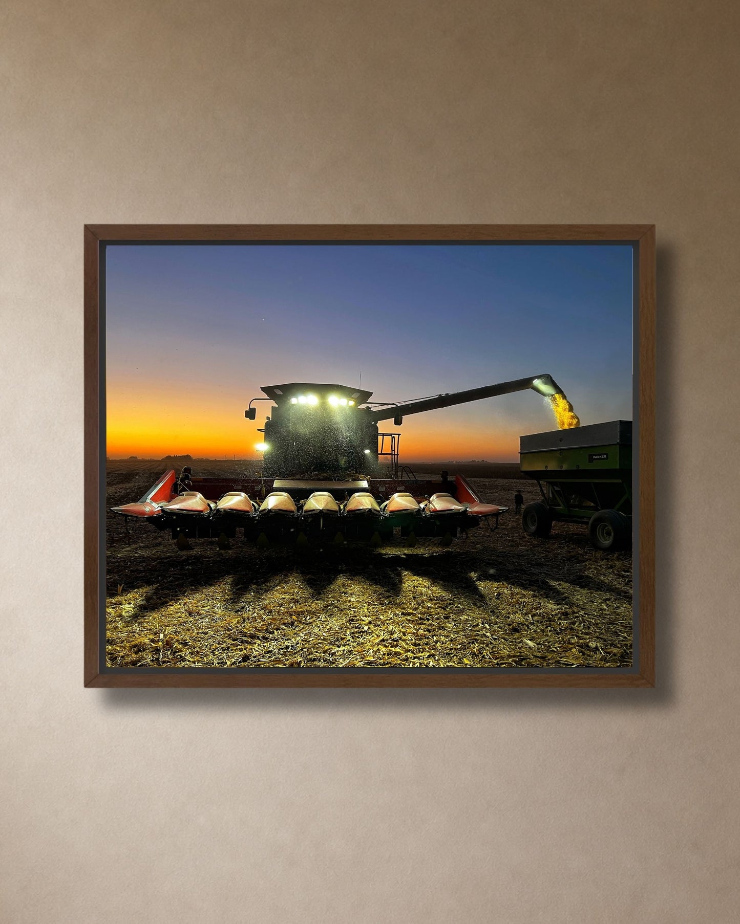 Combine harvest at sunset canvas wall art displayed above a stone fireplace in a cozy farmhouse living room.