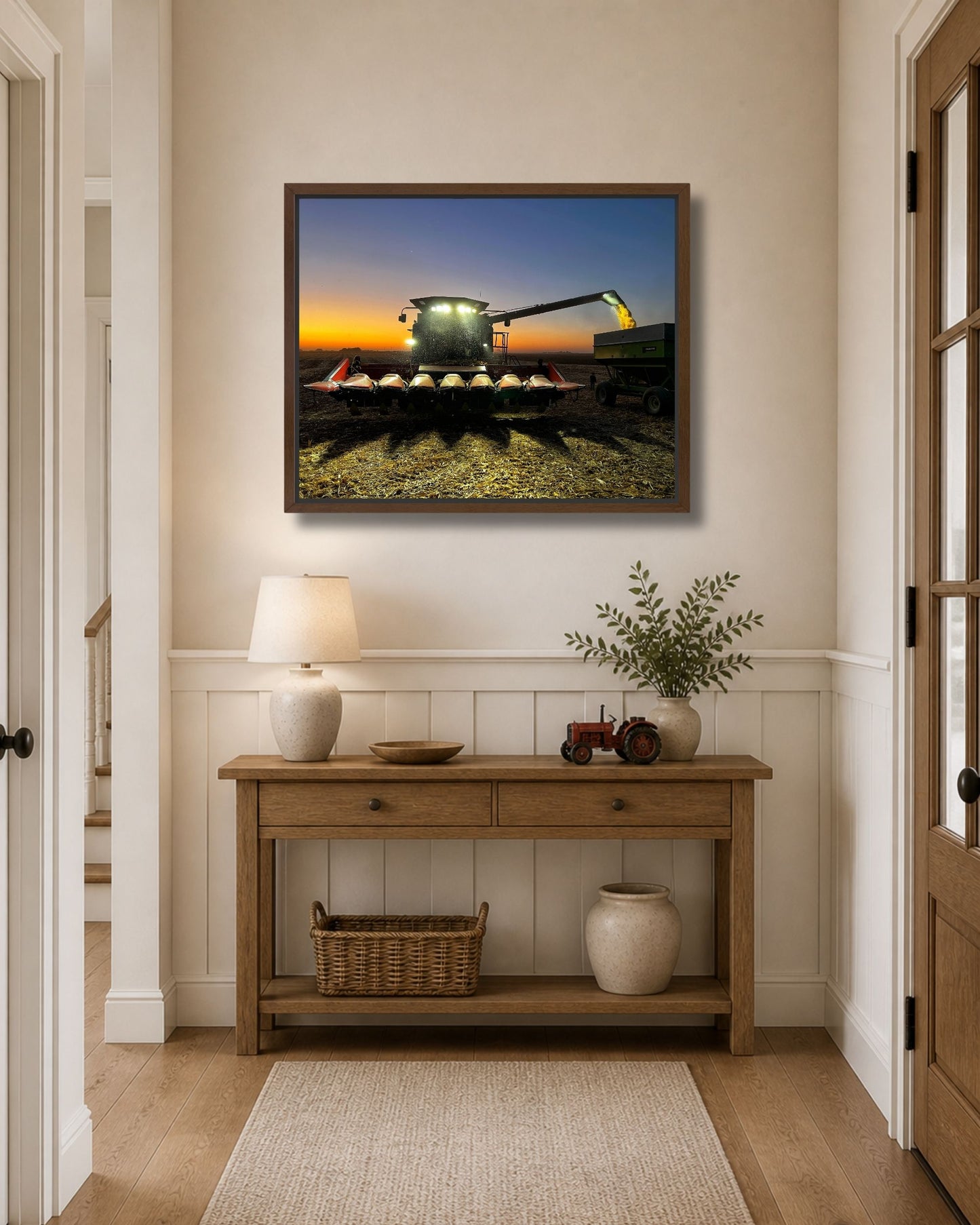 Black framed canvas print of a nighttime corn harvest scene with combine lights glowing at sunset.