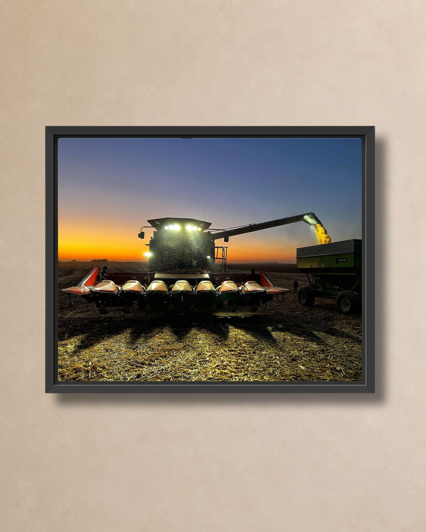 Natural oak framed canvas print of a combine unloading corn at dusk in an Iowa farm field.