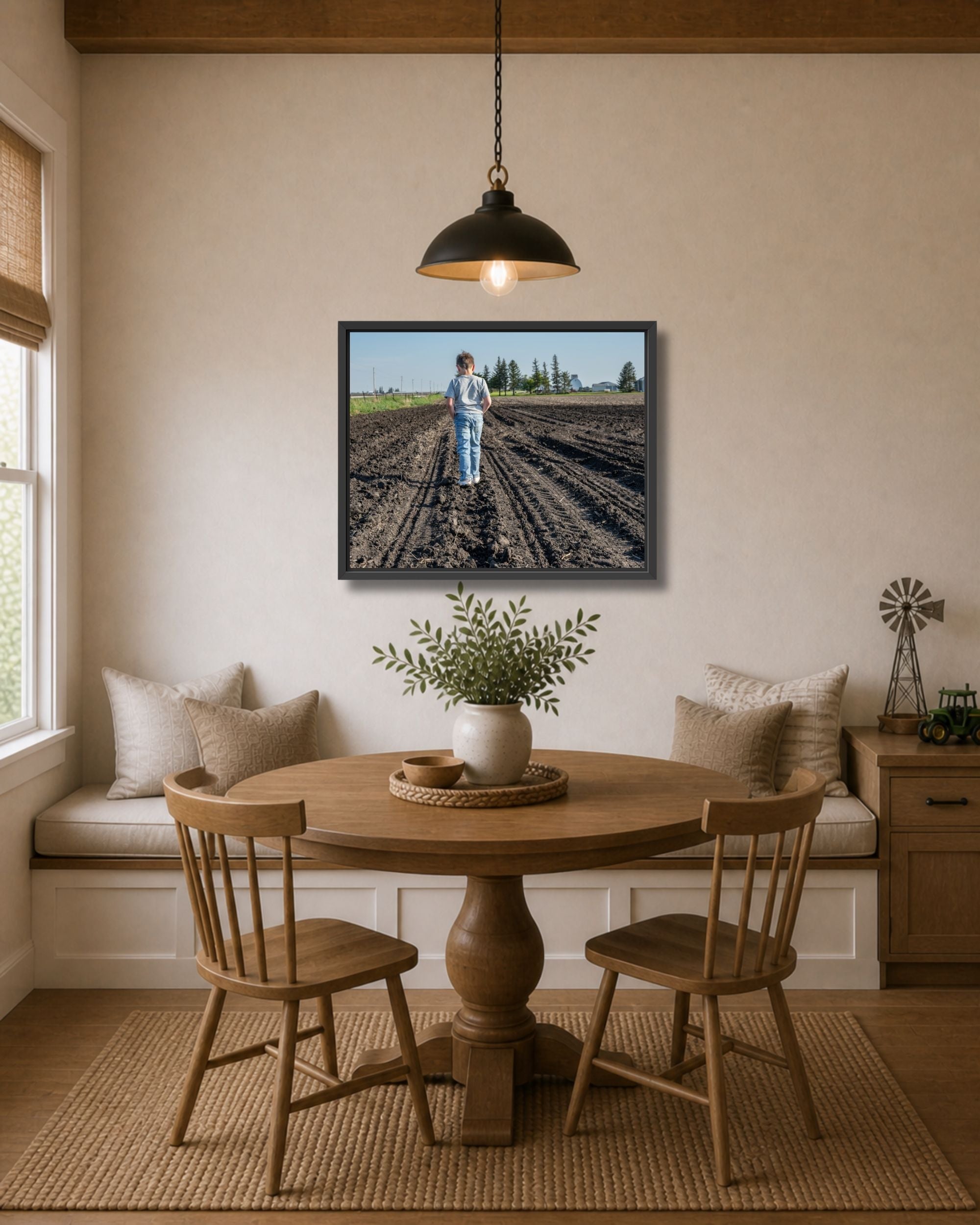 Black framed farm kid canvas wall art displayed in a cozy dining nook with wood table, bench seating, and farmhouse accents.