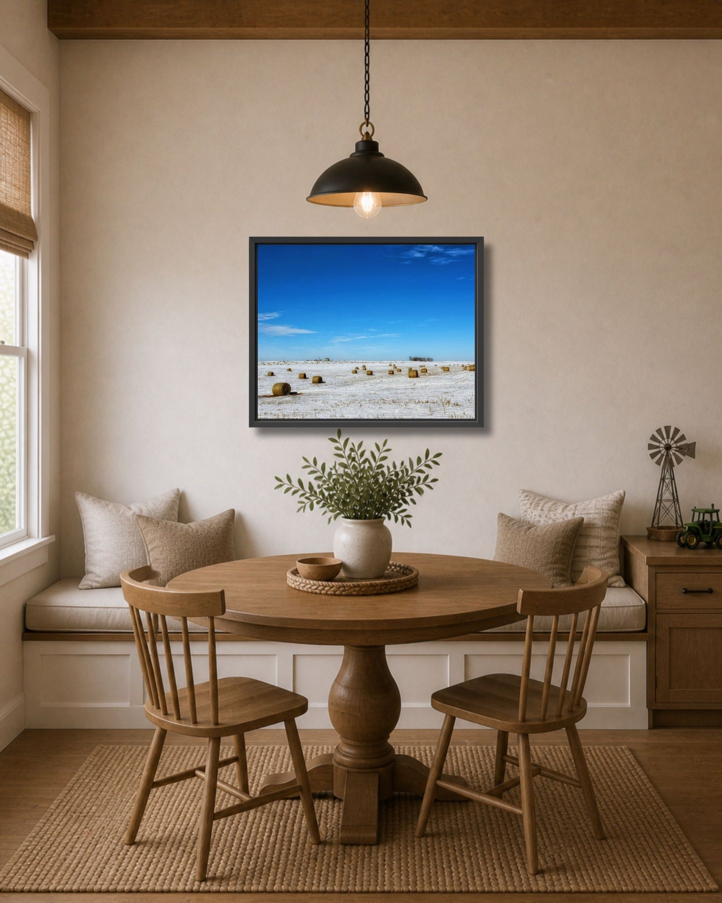 Black framed snowy rural landscape wall art displayed above a breakfast nook table in a warm modern farmhouse interior.