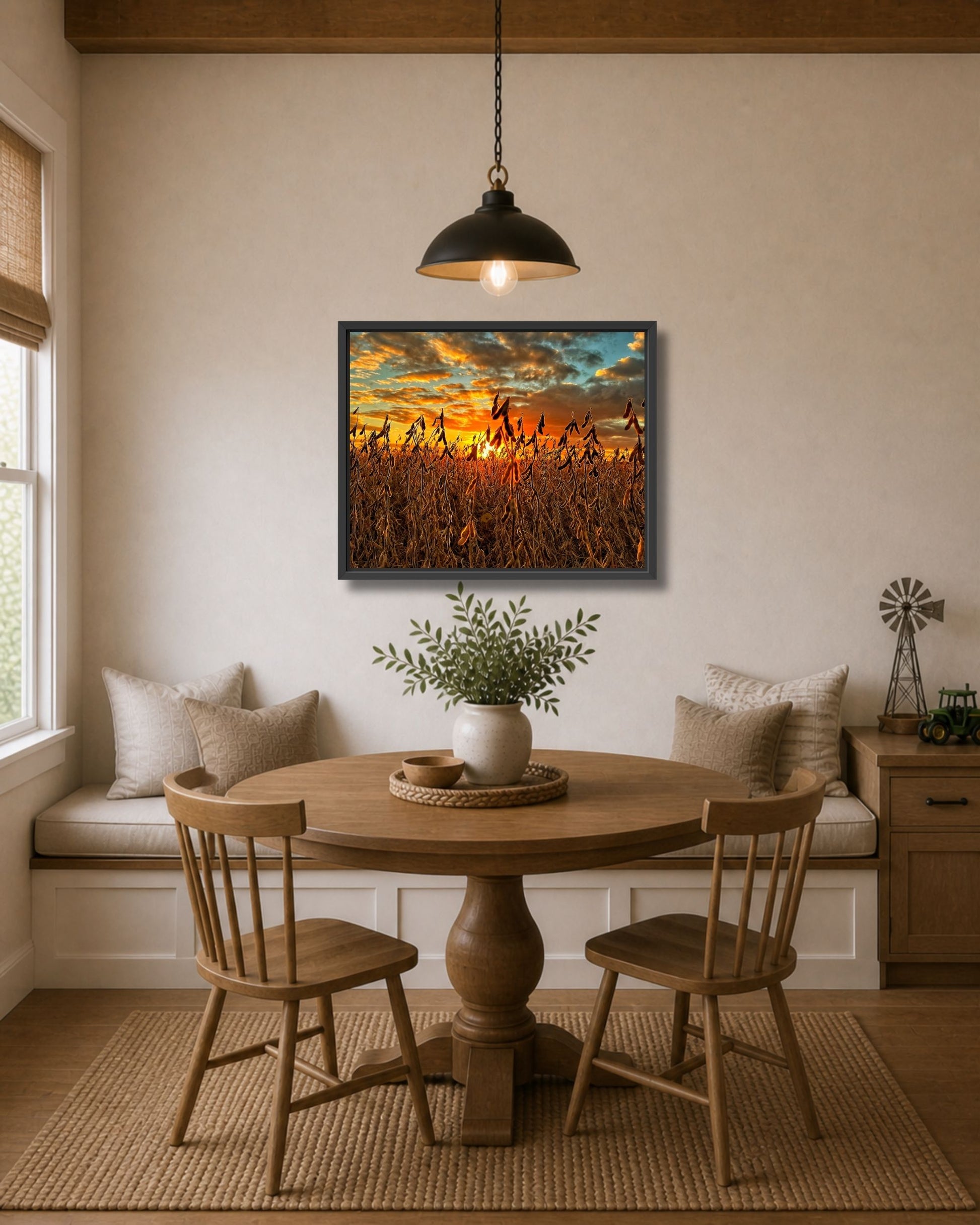 Black framed soybean sunset wall art displayed above a round dining table in a warm farmhouse breakfast nook.
