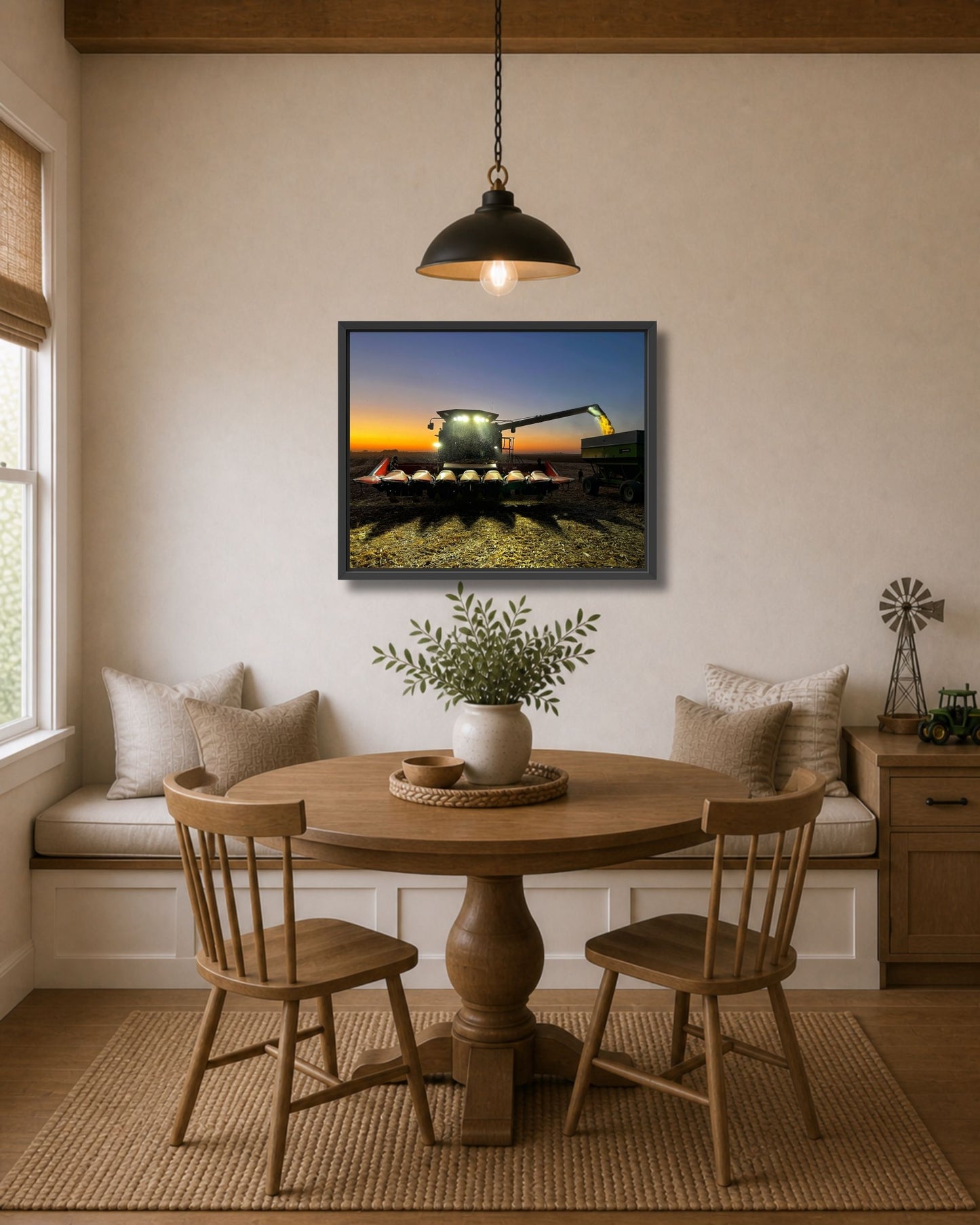 Black framed combine harvest wall art displayed above a round wood dining table in a cozy farmhouse nook.